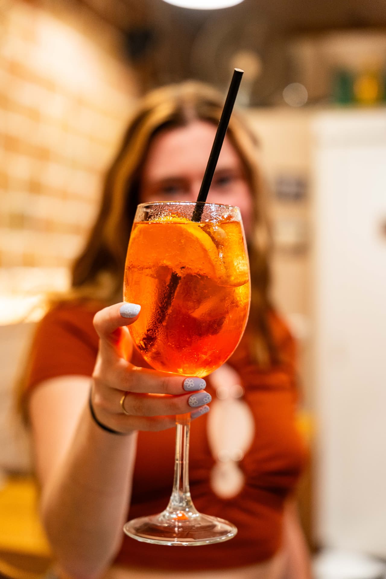 Guest holding up an orange spritz cocktail
