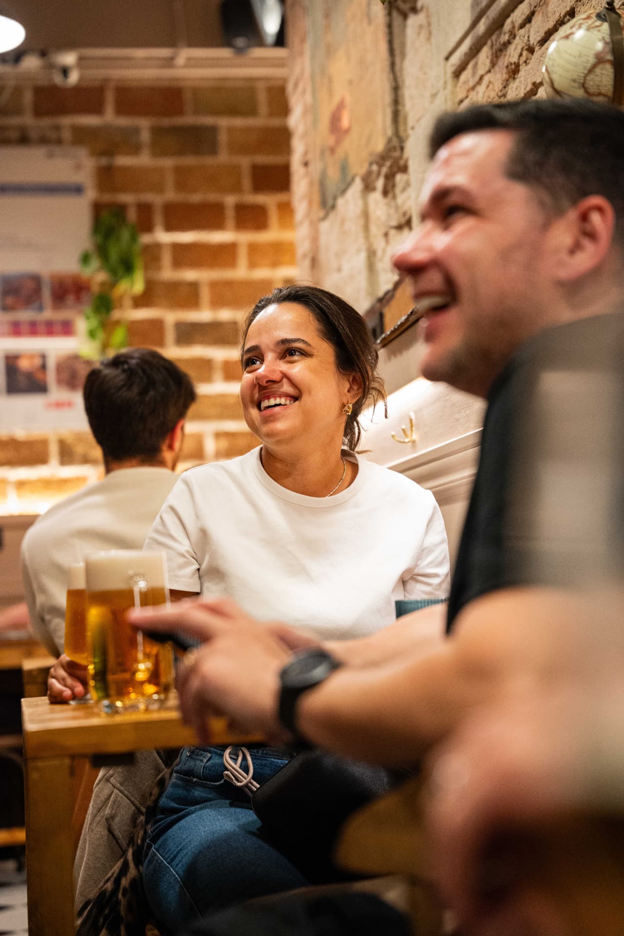 Guests laughing over cold beers by the brick wall